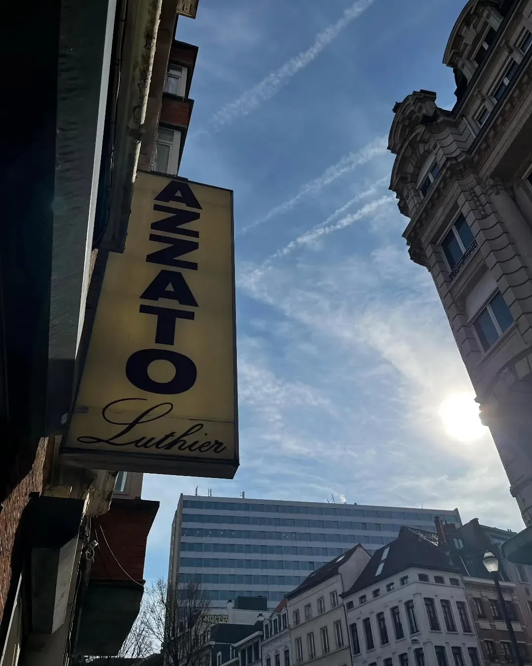 Enseigne « Azzato Luthier » suspendue au-dessus de la rue, à Bruxelles