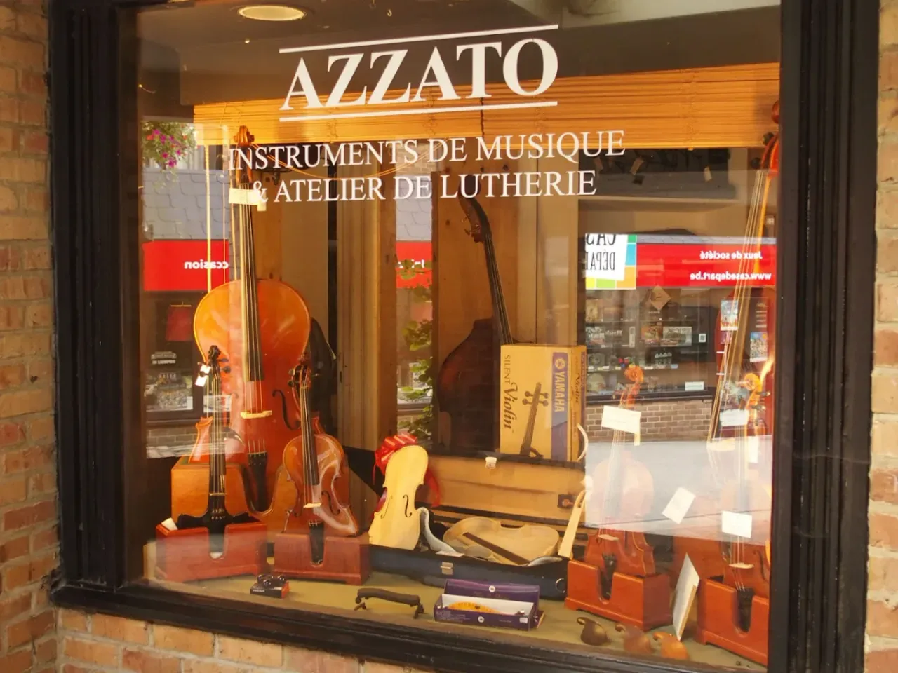 De etalage van de winkel in Louvain-la-Neuve: violen en cello’s achter het geschilderde uithangbord