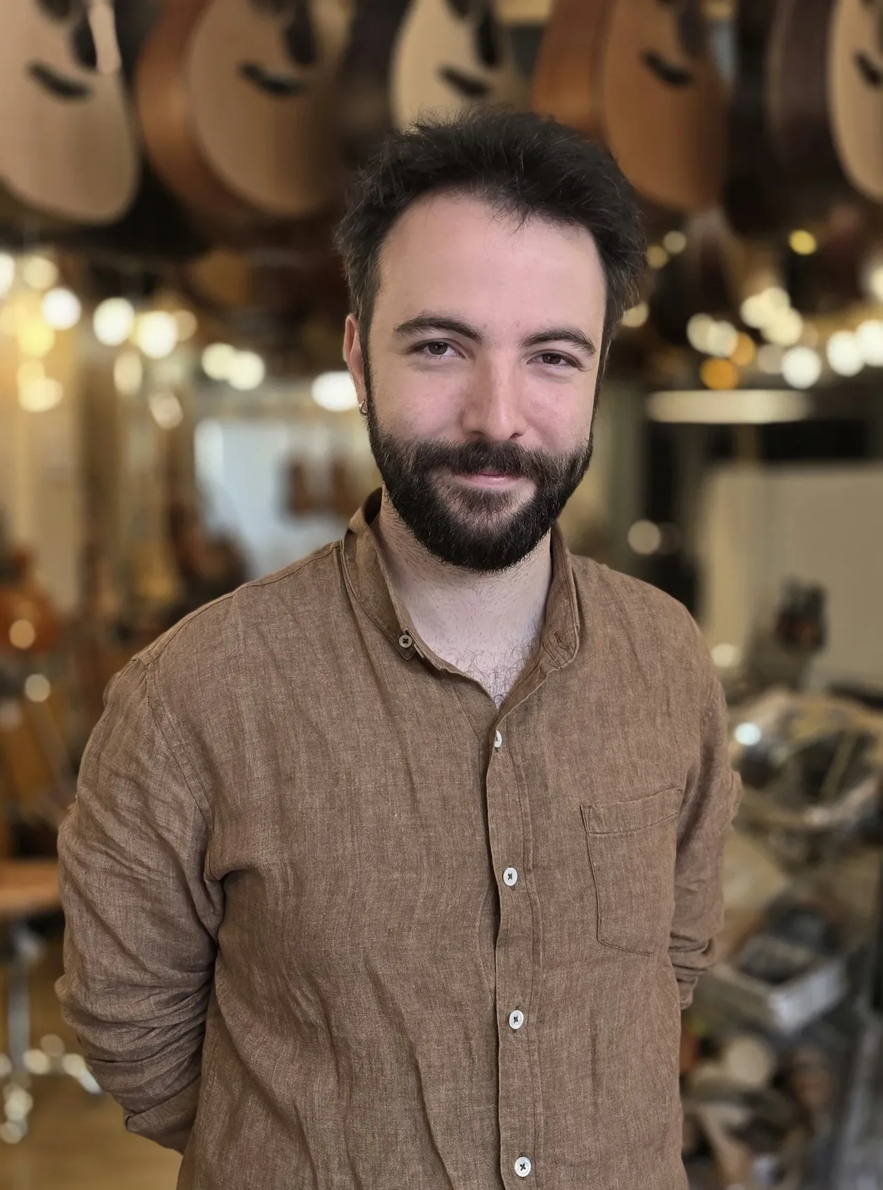 Anthony devant le mur de guitares du magasin de Bruxelles