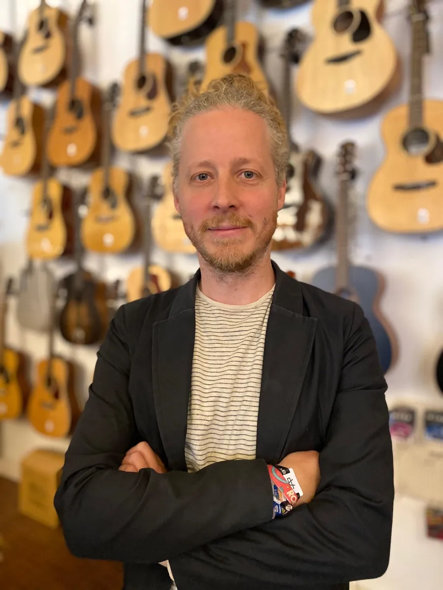Gaëtan, de l’équipe Azzato, devant le mur de guitares du magasin