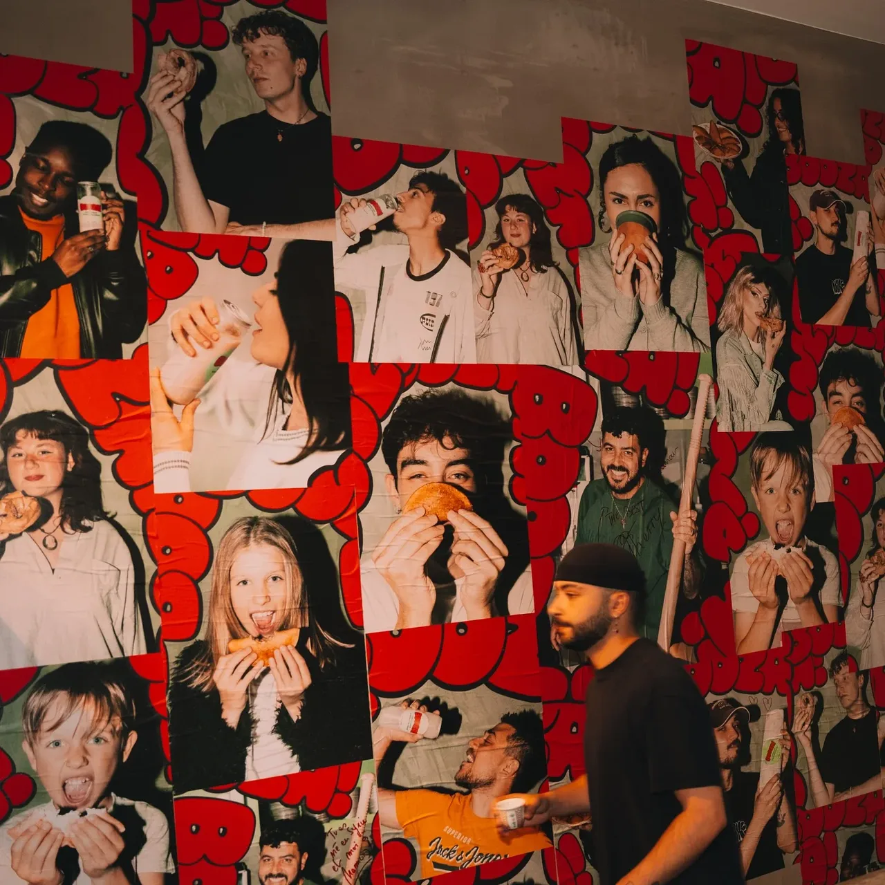 Mur d'affiches Booza! dans le café : portraits de clients qui croquent dans leur glace, encadrés de lettres rouges