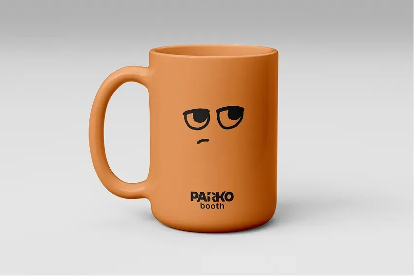 Mug orange Parko Booth avec les yeux levés au ciel et la bouche boudeuse de la mascotte, logo noir en pied