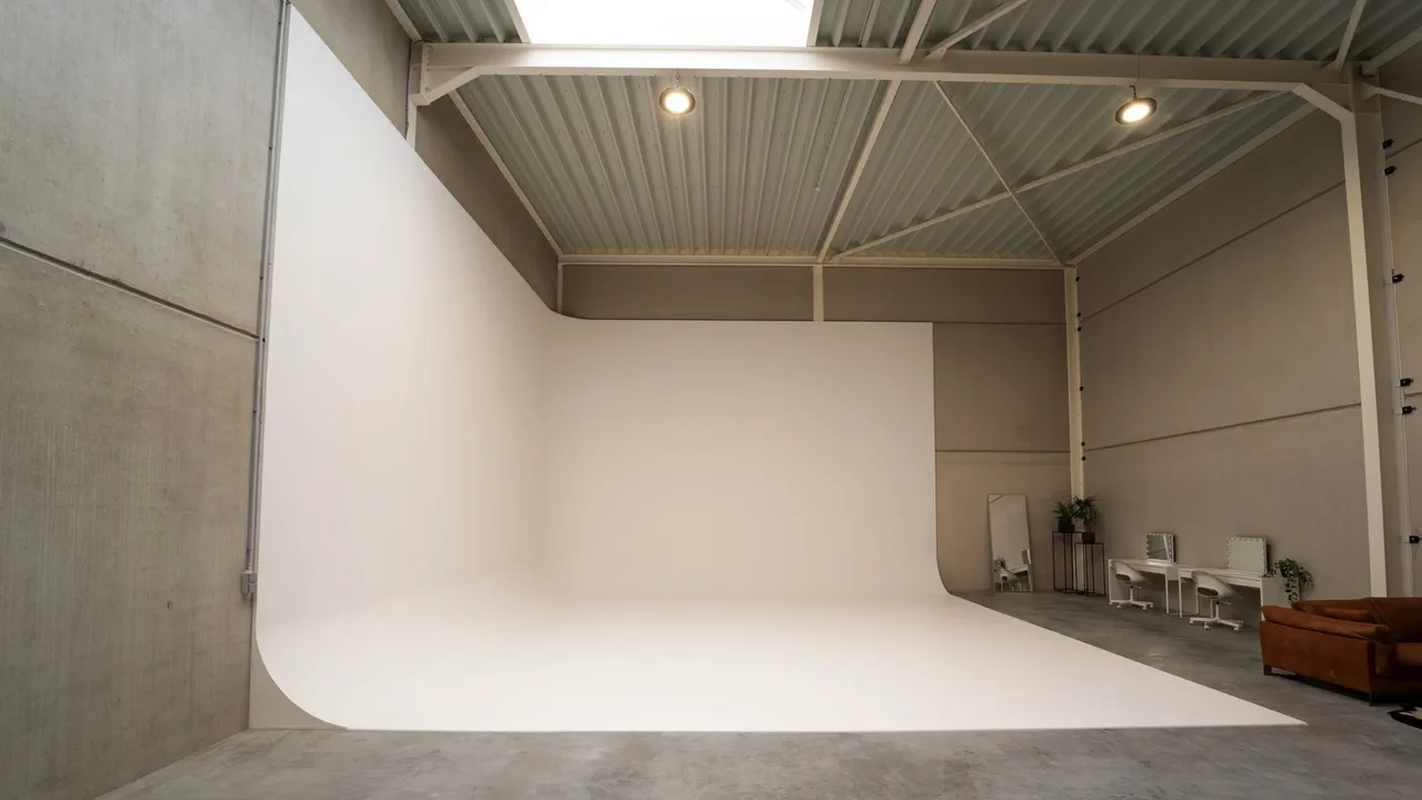 Plateau du studio photo Parko à Wavre : grand cyclo blanc, coin maquillage et canapé