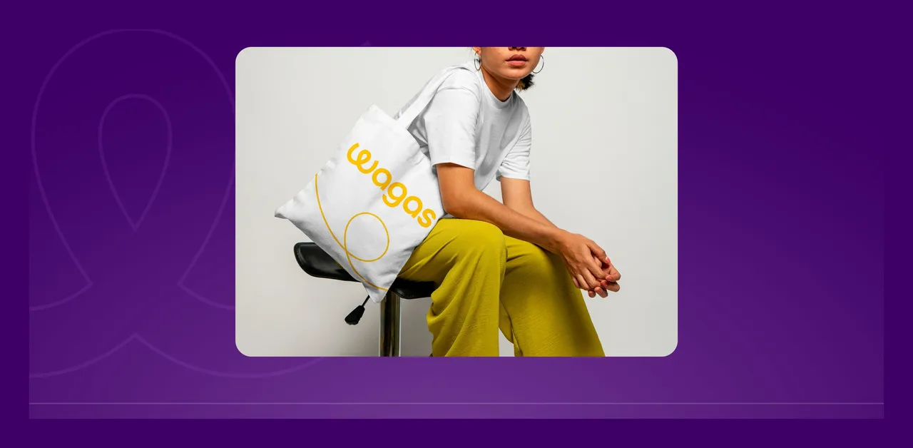 Tote bag blanc au logo Wagas jaune porté à l'épaule, présenté sur fond violet