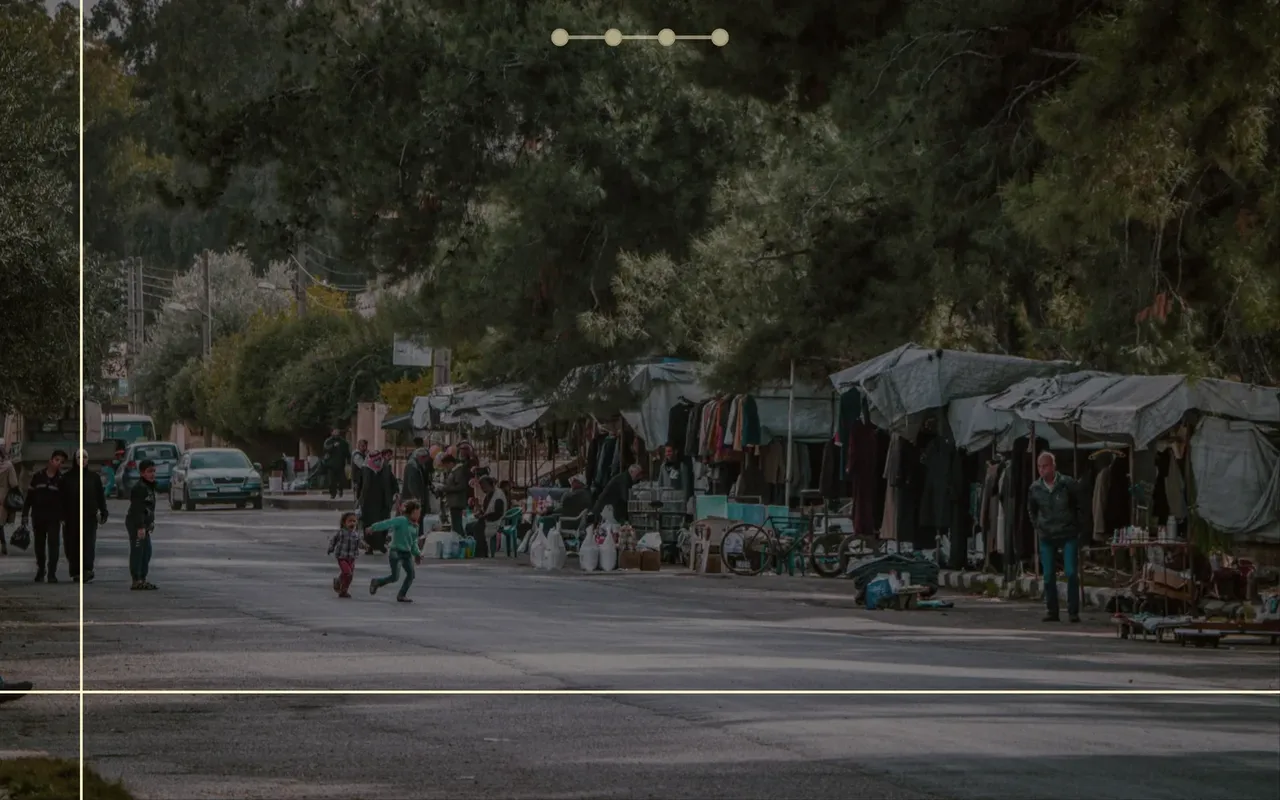 Rue de marché en Syrie en plein écran, avec la frise de navigation du parcours de Georges Baghdi Sar